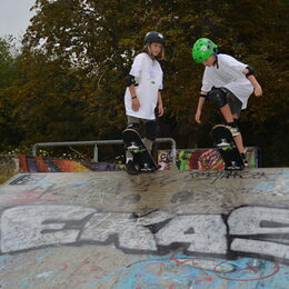 zwei Kinder auf einem Skateboard an einer Rampe stehend