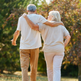 Mann und Frau in höherem Alter spazieren zusammen im Grünen
