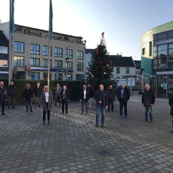 Ein Gruppe von Personen, 14 Männer und eine Frau, stehen mit jeweils 2 Meter Abstand auf dem Platz vor dem Medio Rhein-Erft in Bergheim