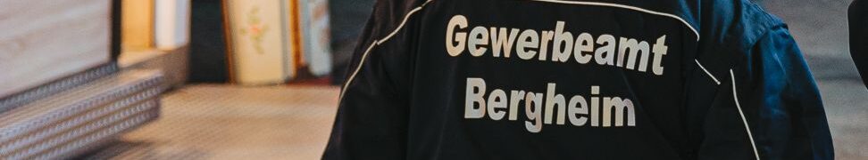 Frau mit Uniform, auf der Rückseite Schriftzug "Gewerbeamt Bergheim" abends auf einer Kirme