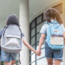 zwei Kinder gehen Hand in Hand zur Schule