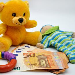 Teddybär und anderes Kinderspielzeug und einige Fünfzig-Euro-Scheine