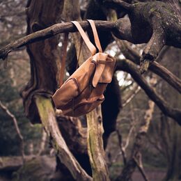 brauner Lederrucksack, der verlassen an einem Baum hängt