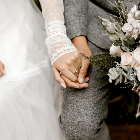 Mann hält Hand einer Frau bei Hochzeit