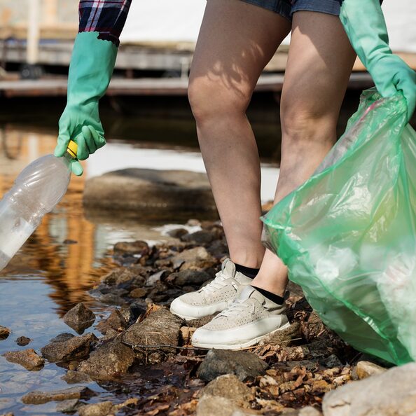 Plastikflasche und Müllbeutel an einem Fluss